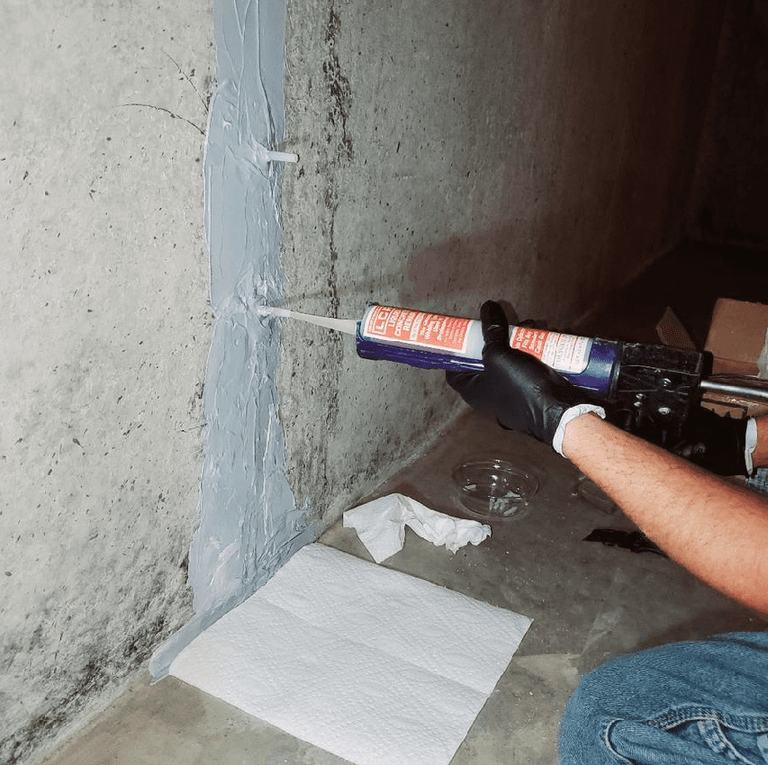 a person using a tube to seal a crack