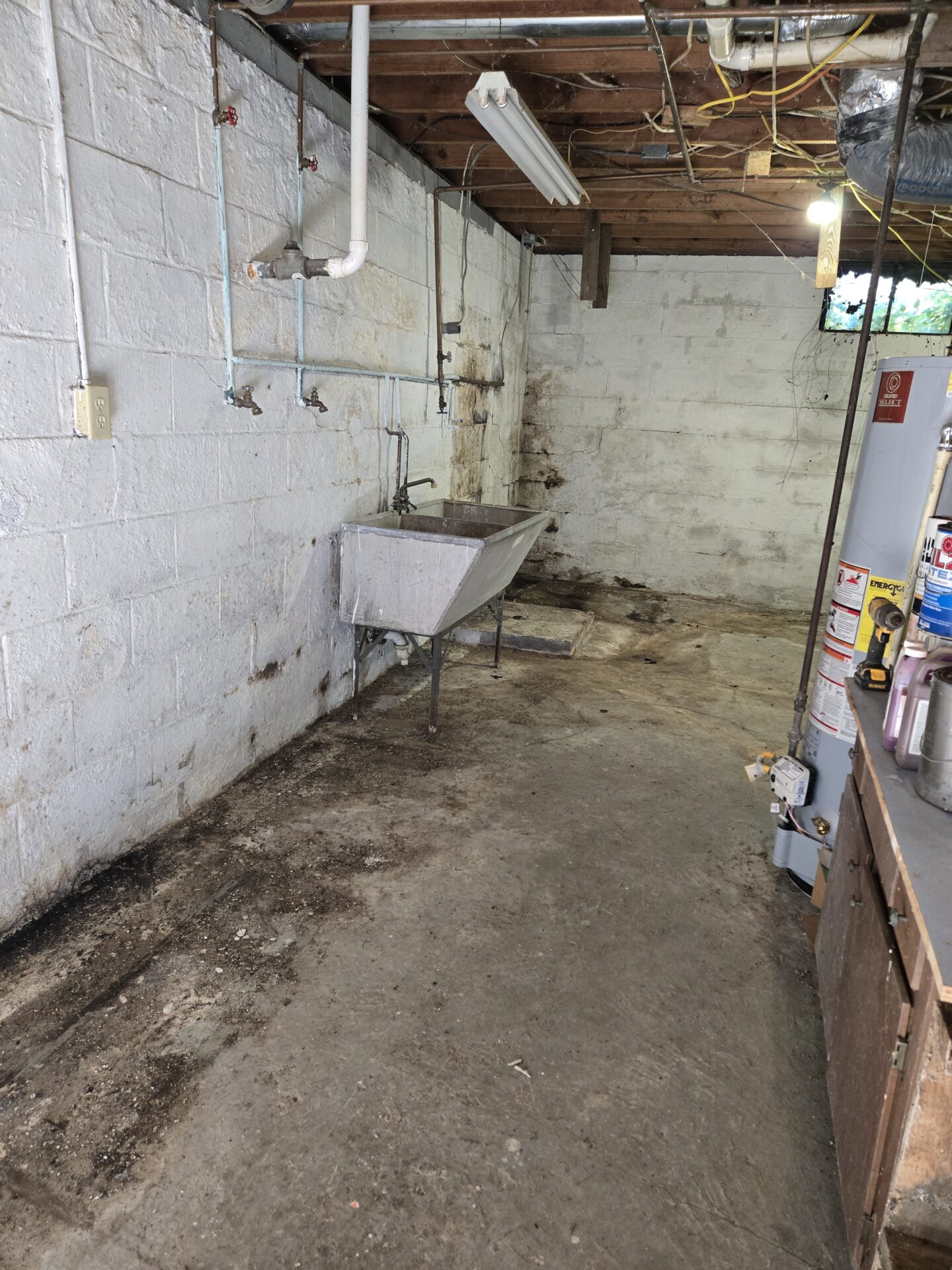 A large, metal sink is situated against one wall, with several exposed pipes and valves above it